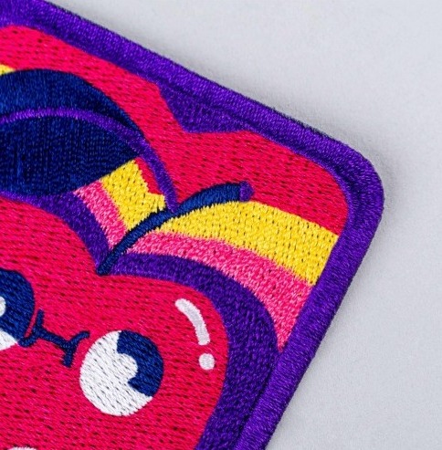 Close-up of a colourful embroidered patch with a purple border